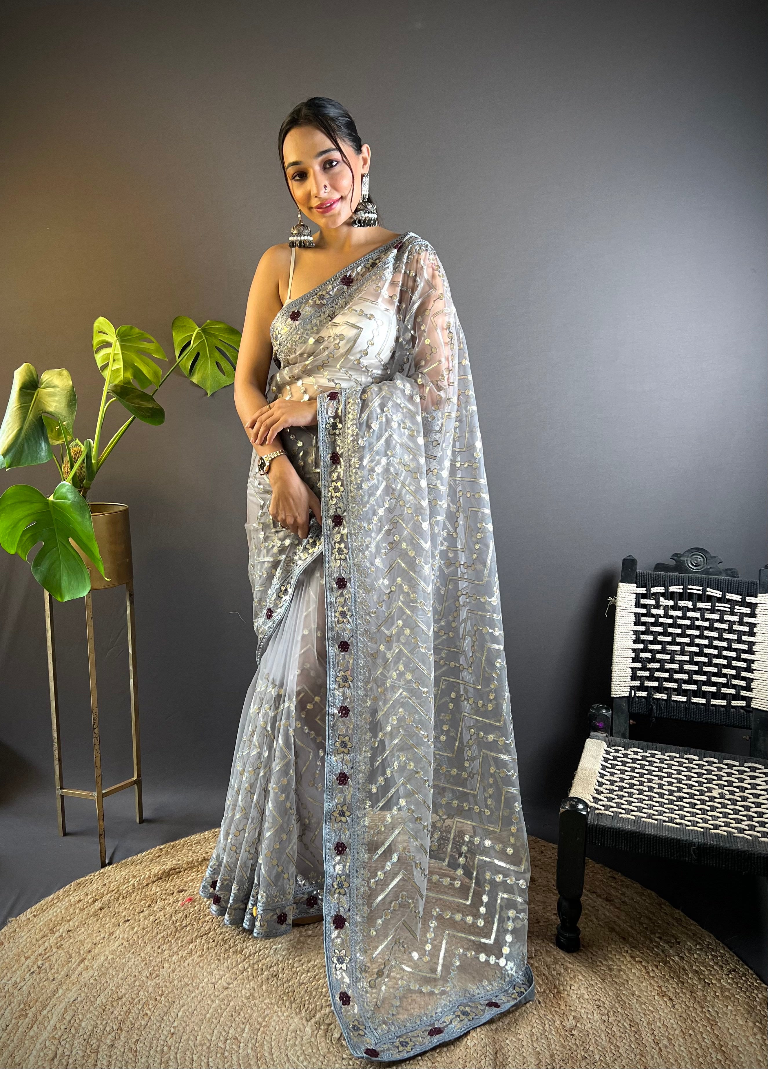 Model wearing a sheer butterfly net saree with geometric chain stitch embroidery, foil thread work, and heavy stone embellished border