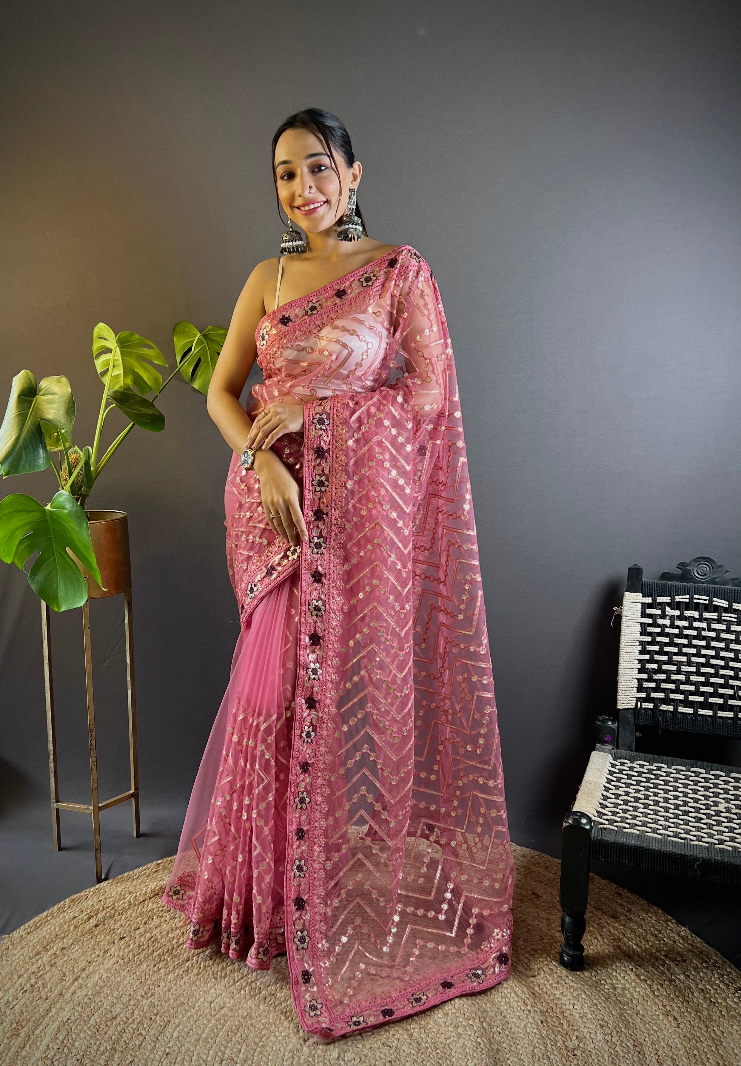 Model wearing a sheer butterfly net saree with geometric chain stitch embroidery, foil thread work, and heavy stone embellished border