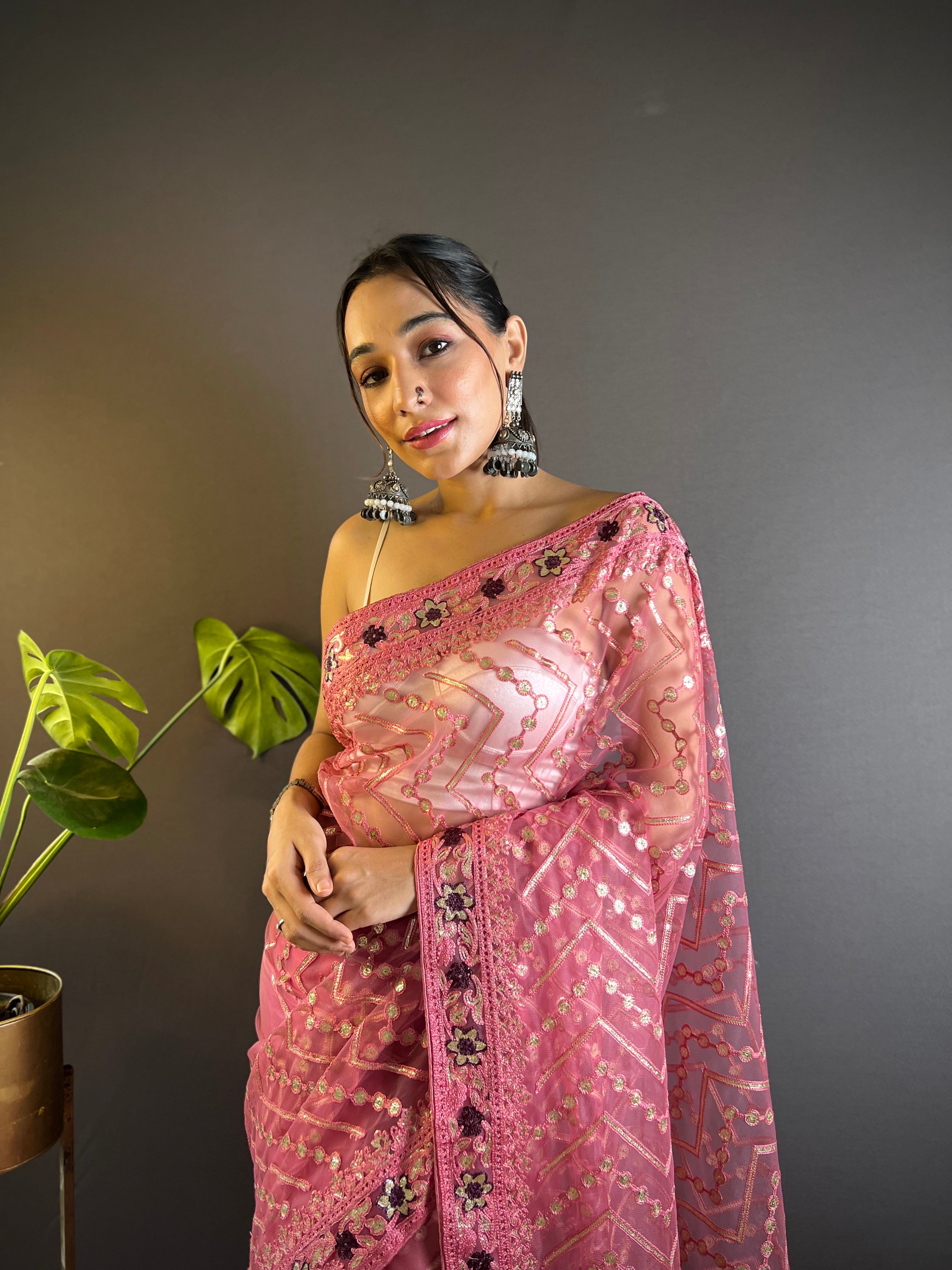 Model wearing a sheer butterfly net saree with geometric chain stitch embroidery, foil thread work, and heavy stone embellished border