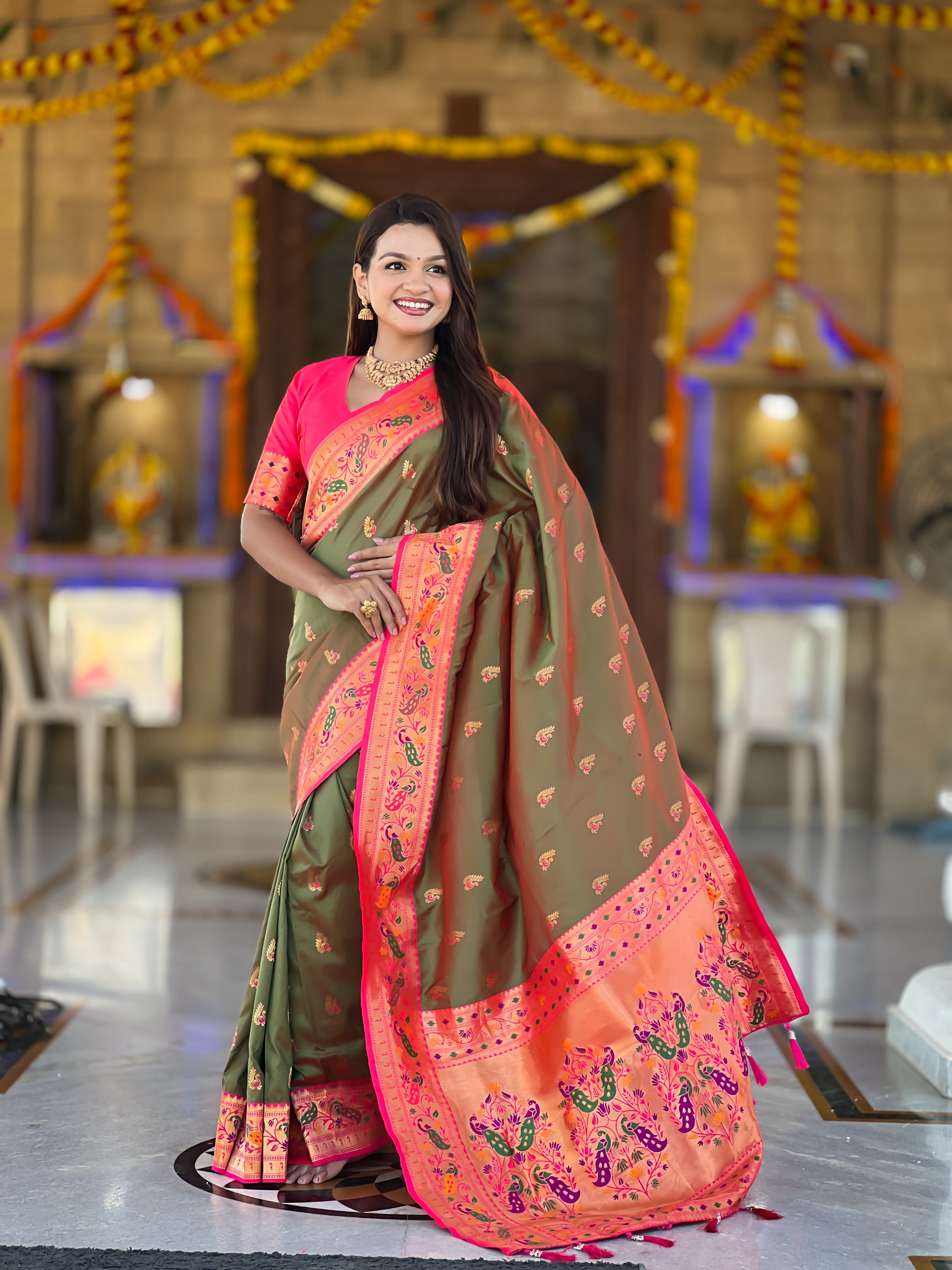 Model wearing a royal soft Paithani silk saree with Meenakari zari weaving and contrast pink border in a traditional temple setting