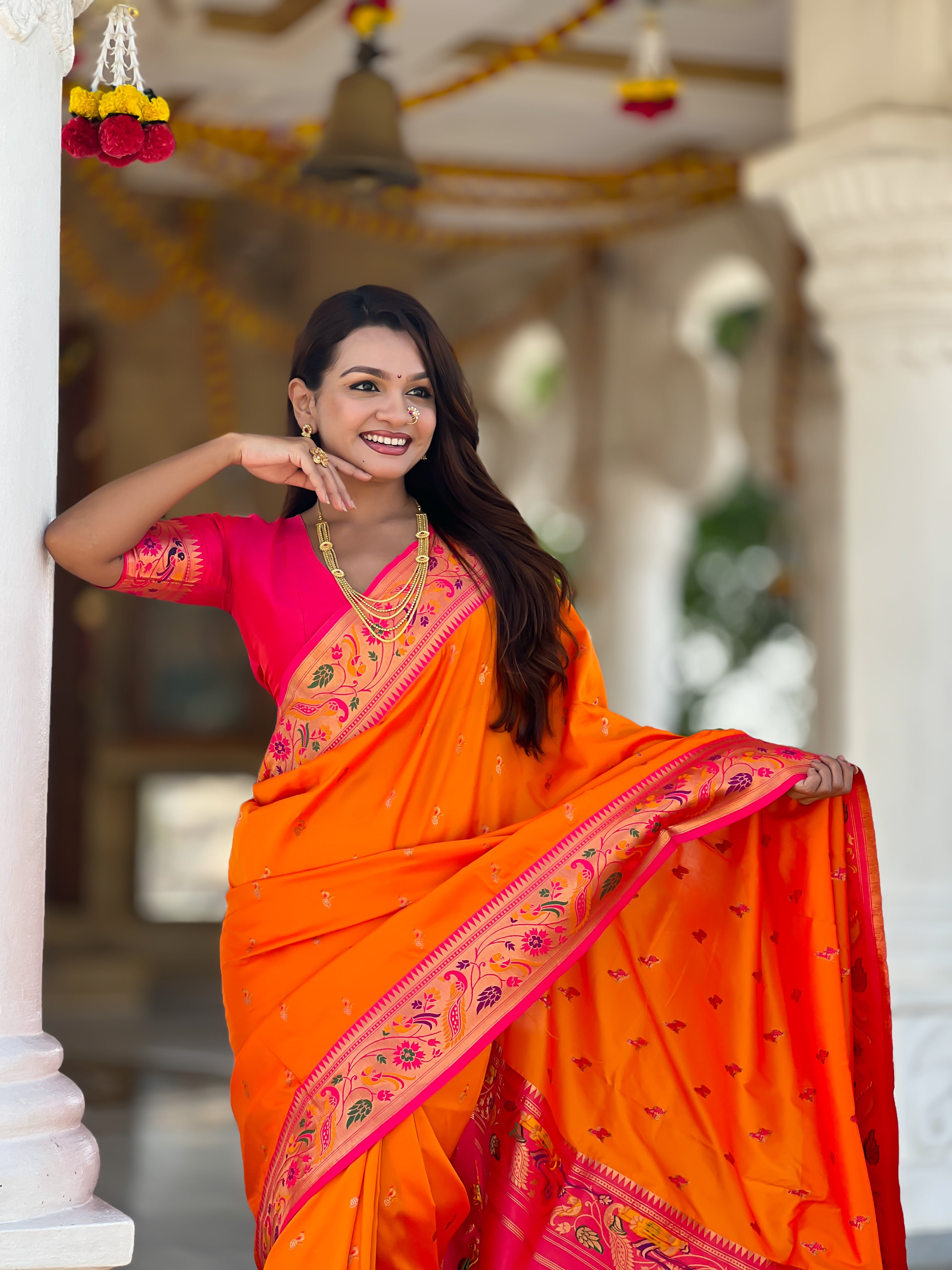 Woman wearing Orange Soft Paithani Silk Saree with pink border and Meenakari Zari weaving motifs