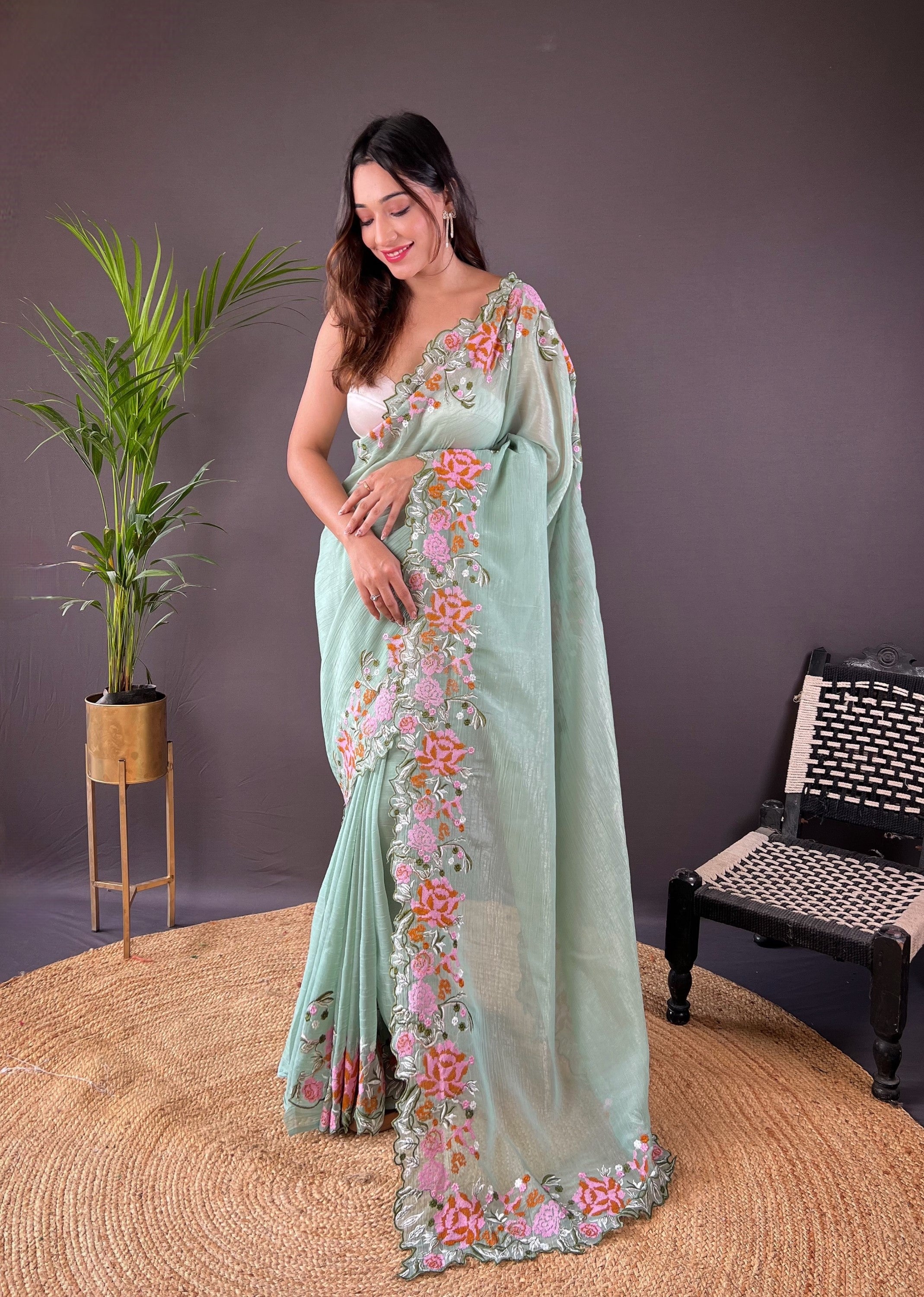 Woman wearing soft glossy silk saree with pink floral cross stitch embroidery and scalloped cutwork border