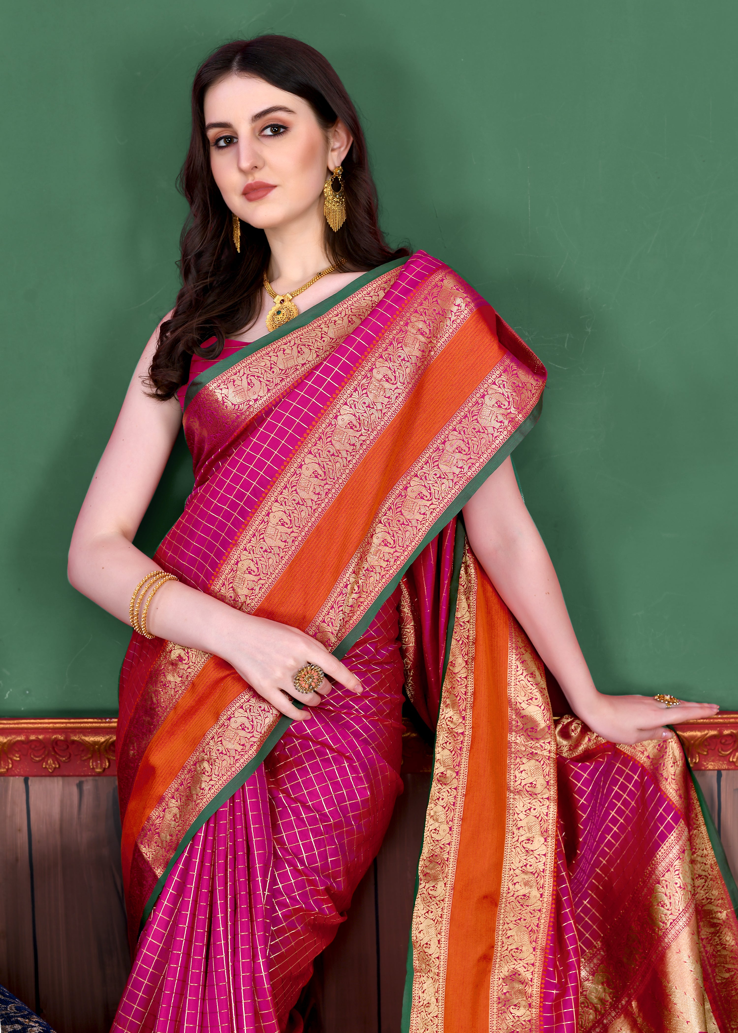 Woman wearing regal Pink soft silk saree with gold zari checks, contrast border, and rich pallu with tassels