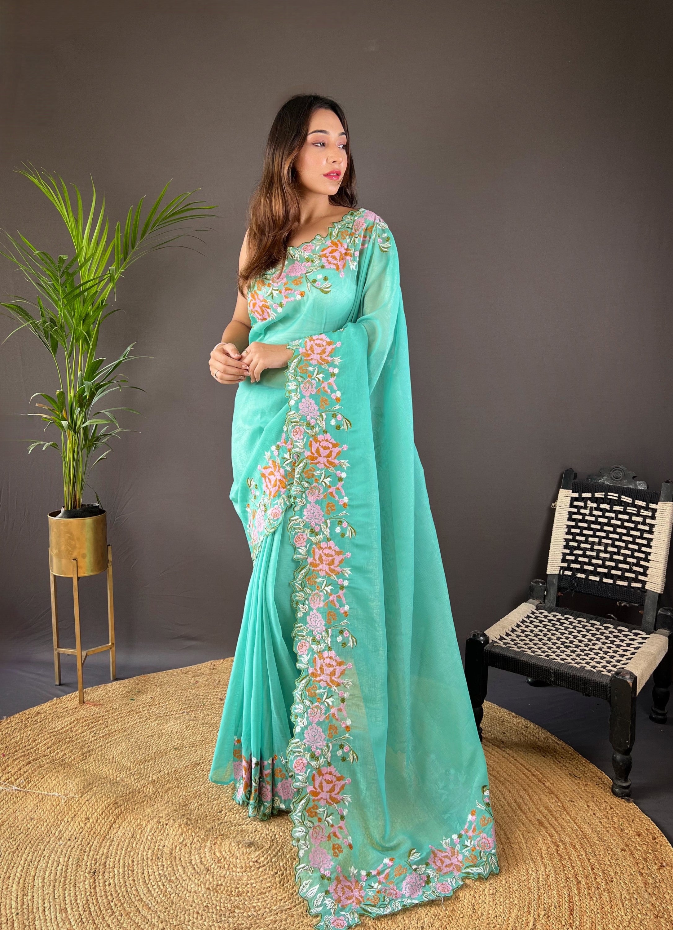 Woman wearing soft glossy silk saree with pink floral cross stitch embroidery and scalloped cutwork border