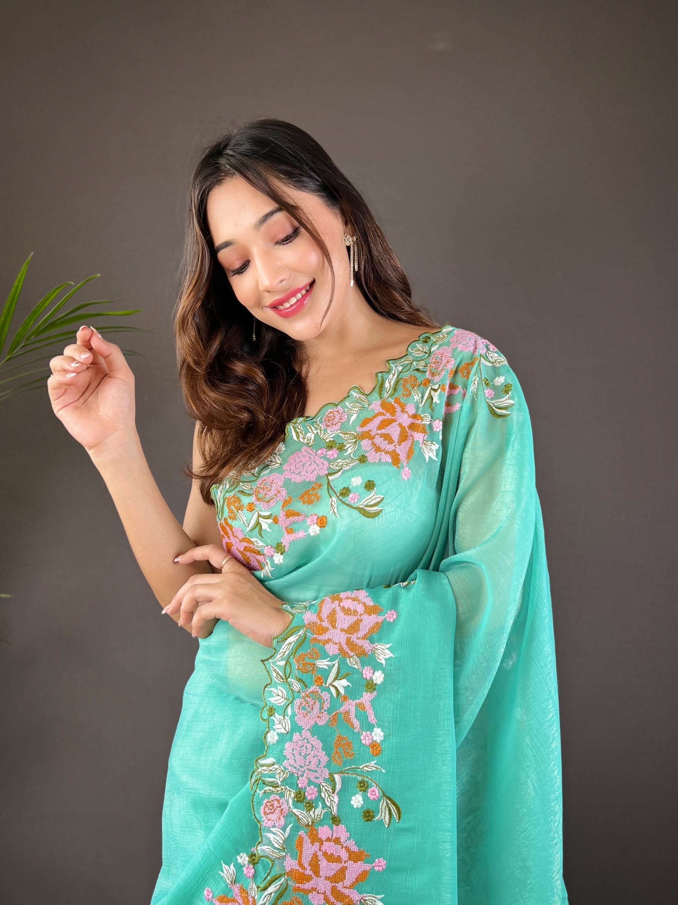 Woman wearing soft glossy silk saree with pink floral cross stitch embroidery and scalloped cutwork border