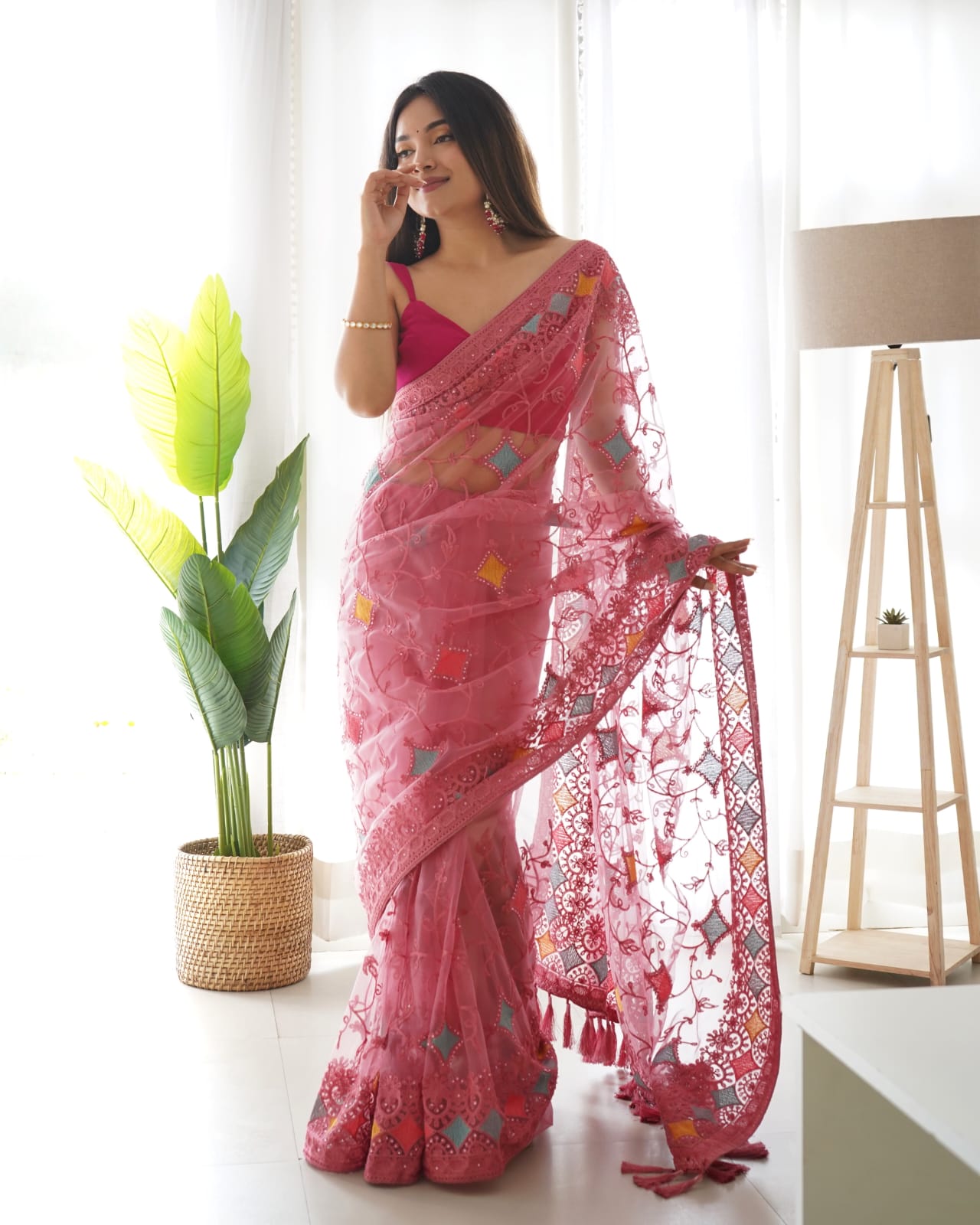 Woman wearing pink heavy butterfly net saree with multi-color aari embroidery and stone work details