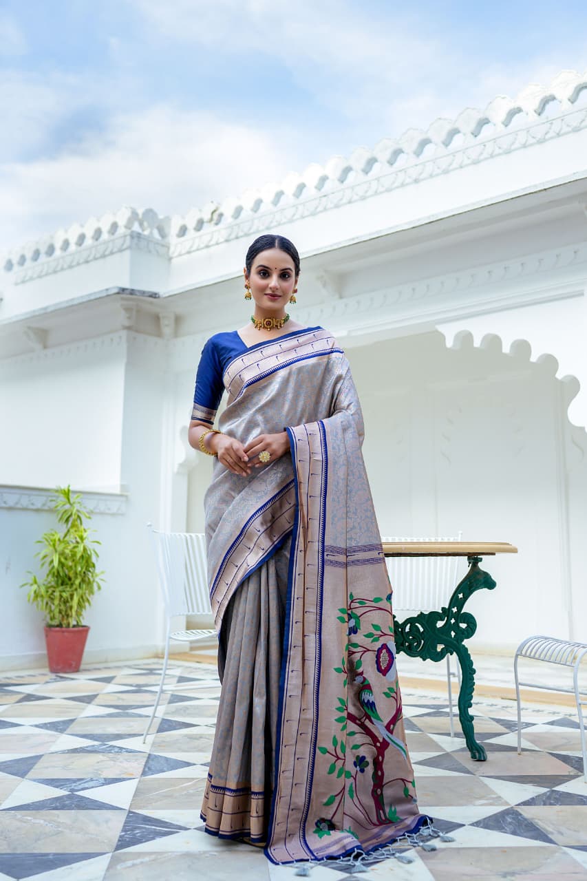 Model wearing grey Kanchi-Paithani fusion silk saree with blue border and colorful bird motif pallu standing in heritage courtyard