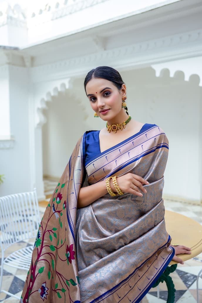 Model wearing grey Kanchi-Paithani fusion silk saree with blue border and colorful bird motif pallu standing in heritage courtyard