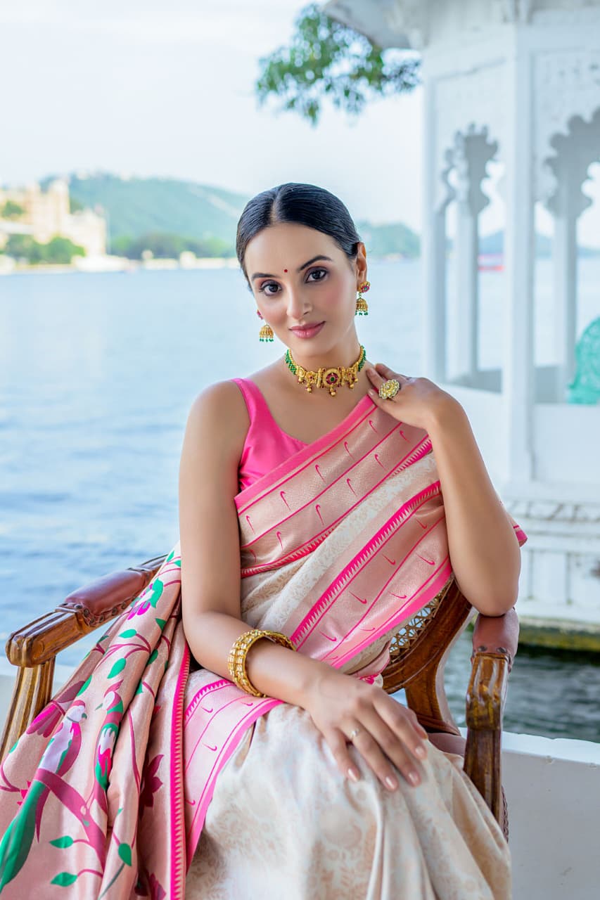 Model wearing grey Kanchi-Paithani fusion silk saree with blue border and colorful bird motif pallu standing in heritage courtyard