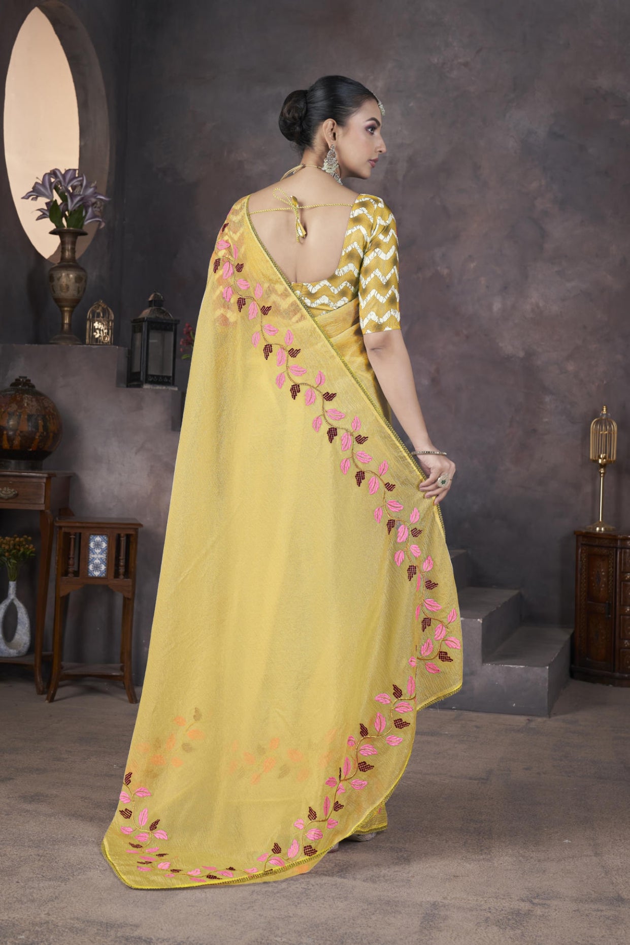 Model wearing Yellow soft crush georgette saree with blue leaf thread embroidery and chevron batik blouse