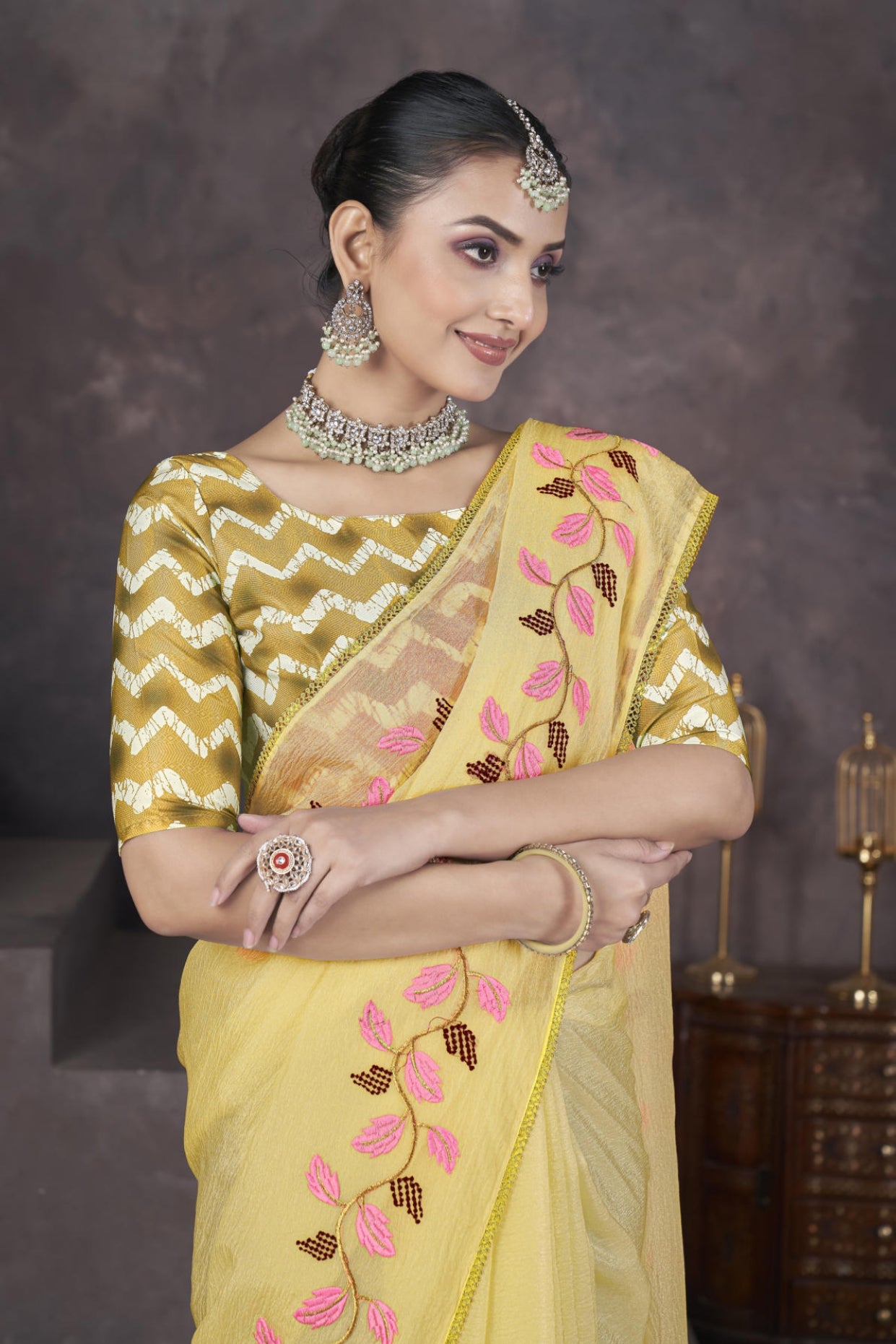 Model wearing Yellow soft crush georgette saree with blue leaf thread embroidery and chevron batik blouse