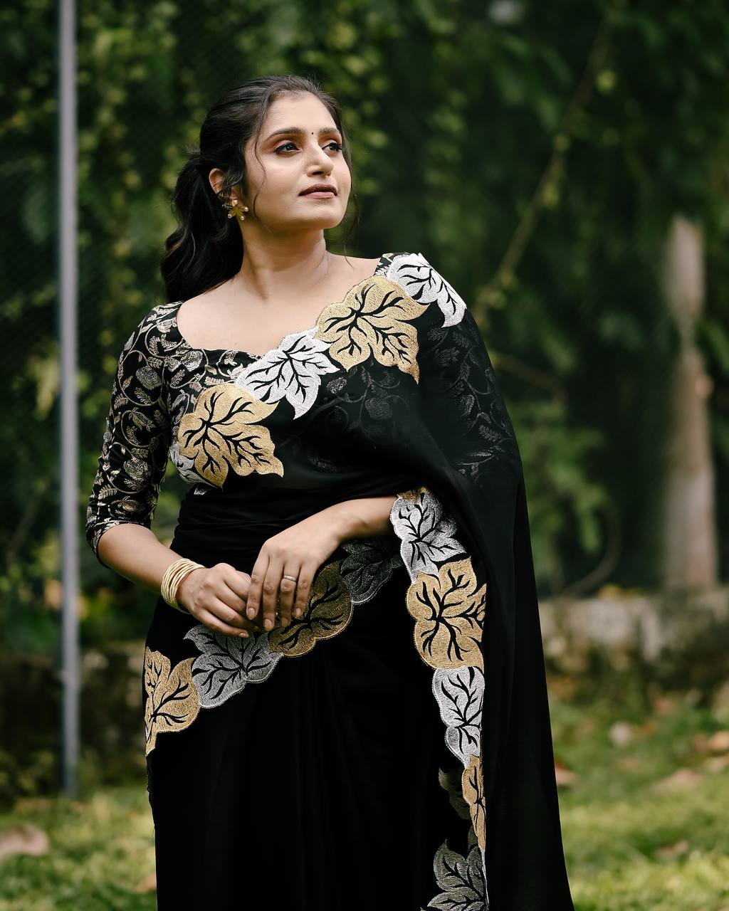 Woman wearing satin chiffon silk saree with large leaf jari embroidery and cutwork border