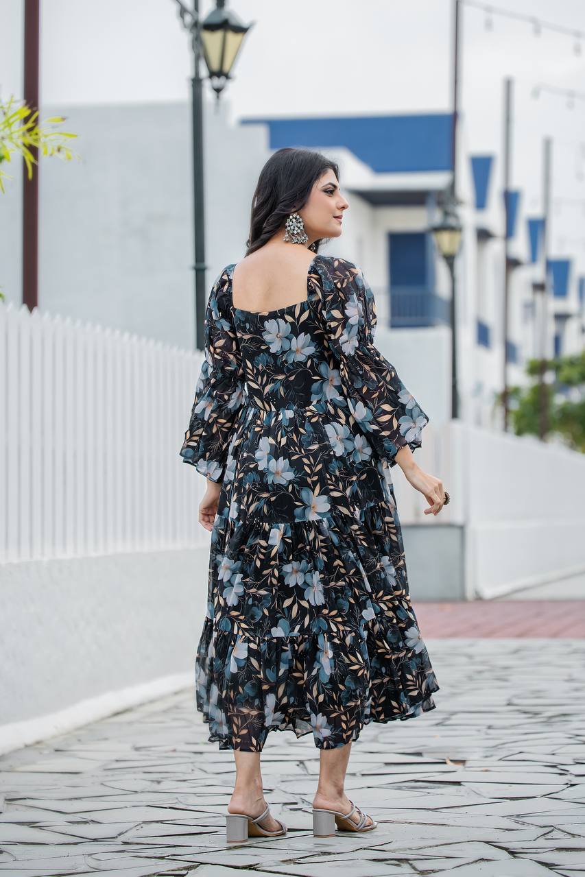 Model wearing black floral print georgette gown with tiered skirt and bell sleeves spinning outdoors