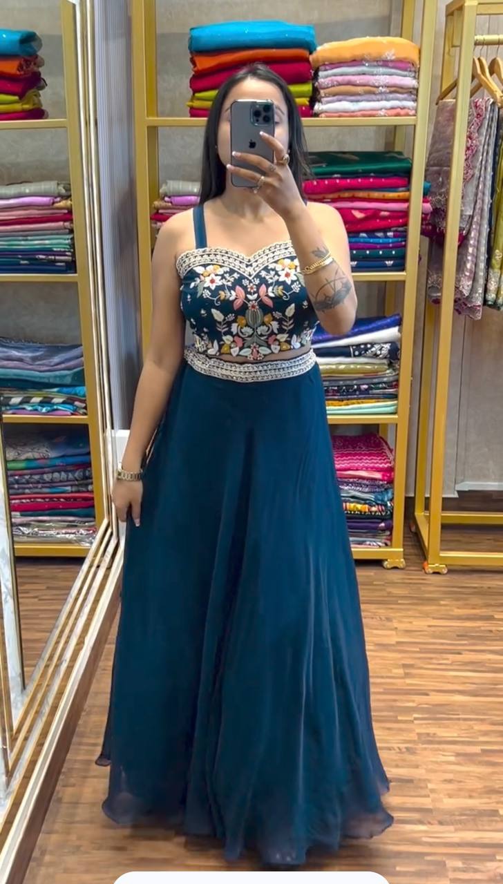 Woman wearing teal jacket lehenga set with floral sequin embroidery and scalloped edges looking in mirror