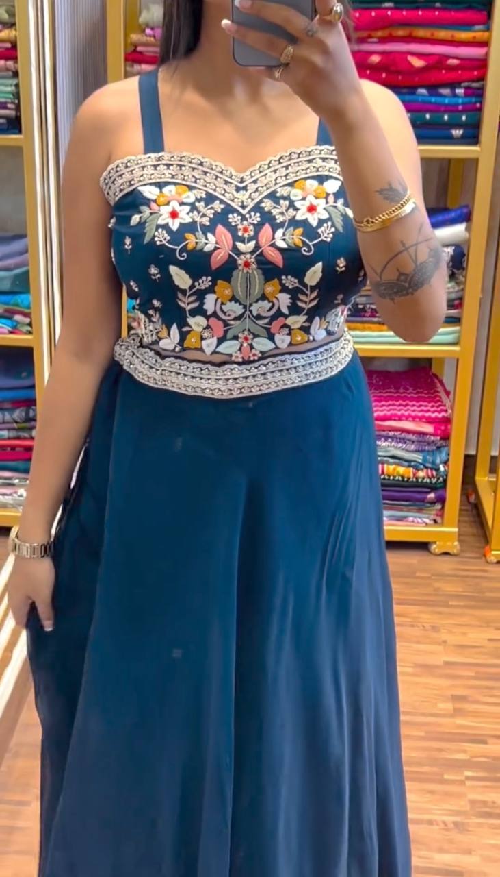 Woman wearing teal jacket lehenga set with floral sequin embroidery and scalloped edges looking in mirror